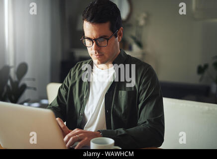L'homme à travailler sérieusement sur l'ordinateur portable à la maison Banque D'Images