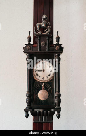 Old vintage grand-père en bois sombre sculpté sur bois horloge murale pendaison mur blanc pilier Banque D'Images