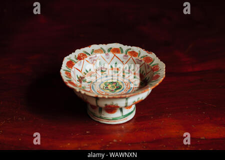 Kaki jaune doux mûrs colorés sur blanc avec fleur rouge socle peint Chine bac ware porcelaine chinoise, sur fond de bois Banque D'Images