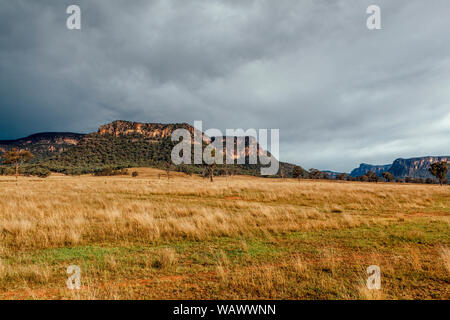 Les plaines herbeuses soutenu par le bush naturel et crêtes de grès dans la vallée Capertee, NSW, Australie Banque D'Images