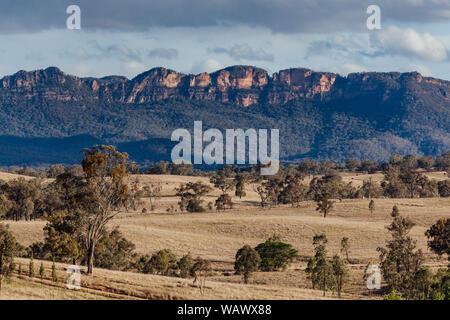 Les plaines herbeuses soutenu par le bush naturel robuste et crêtes de grès dans la vallée Capertee, NSW, Australie Banque D'Images