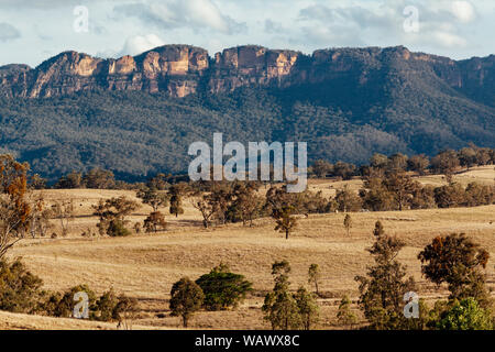 Les plaines herbeuses soutenu par le bush naturel robuste et crêtes de grès dans la vallée Capertee, NSW, Australie Banque D'Images