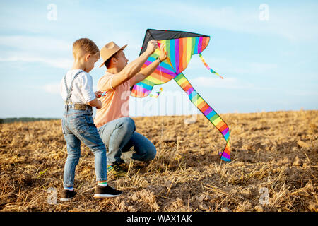 Père fils colorés avec le lancement d'air kite sur le terrain. Concept d'une famille heureuse s'amusant pendant l'activité estivale Banque D'Images