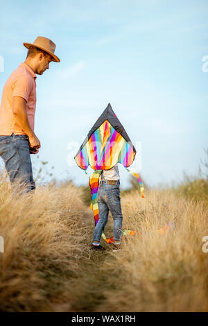 Père fils colorés avec le lancement d'air kite sur le terrain. Concept d'une famille heureuse s'amusant pendant l'activité estivale Banque D'Images