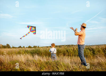 Père fils colorés avec le lancement d'air kite sur le terrain. Concept d'une famille heureuse s'amusant pendant l'activité estivale Banque D'Images