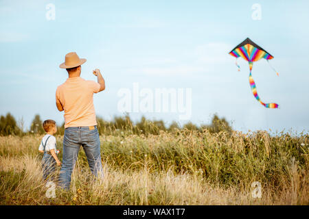 Père fils colorés avec le lancement d'air kite sur le terrain. Concept d'une famille heureuse s'amusant pendant l'activité estivale Banque D'Images