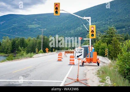 Feux de circulation au début d'un chantier de construction le long d'une route de montagne. Cônes de circulation et les obstacles de la route étroite à une seule voie. Banque D'Images