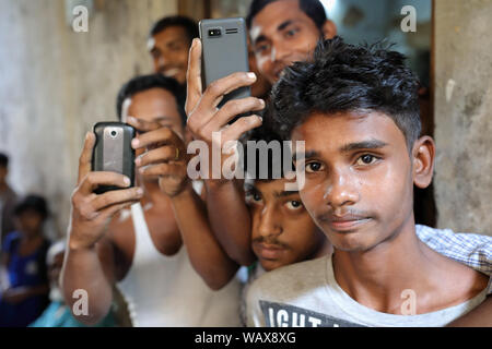Un groupe de jeunes hommes avec des téléphones portables dans les rues du vieux Dhaka, au Bangladesh Banque D'Images