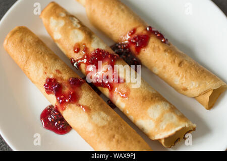 Crêpes russes traditionnelles avec la confiture de framboises sur le dessus. Fines crêpes maison avec croûte croustillante. Maison de vacances la Maslenitsa. Banque D'Images