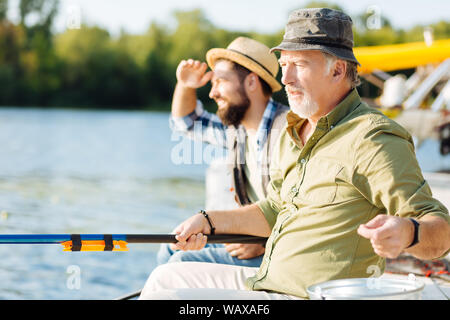 Homme barbu assis près de fils à la retraite et de la pêche Banque D'Images