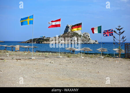 Kos : drapeaux flottants sur la plage d''Agios Stefanos à Kastri island dans l'arrière-plan Banque D'Images