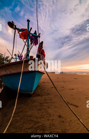 Beau lever de soleil sur un vieux bateau de pêche en bois sur une plage de galets Banque D'Images