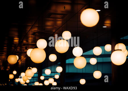 De nombreux lustres et lampes rondes sous plafond. Dans les lampes à la mode noir brillant, intérieur defocused. Les lampes blanches ou claires sur fond sombre éclat. L Banque D'Images