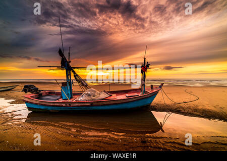 Beau lever de soleil sur un vieux bateau de pêche en bois sur une plage de galets Banque D'Images