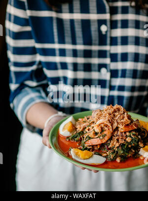 Cuisine thaïlandaise cuisine maison Seablite Seepweed avec salade de crevettes et œuf dur - woman holding dish salade de Seablite Banque D'Images