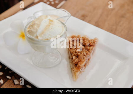 Tarte crumble aux pommes chaud croustillant avec de riches en glace coupe verre blanc sur plaque. Close up shot Banque D'Images