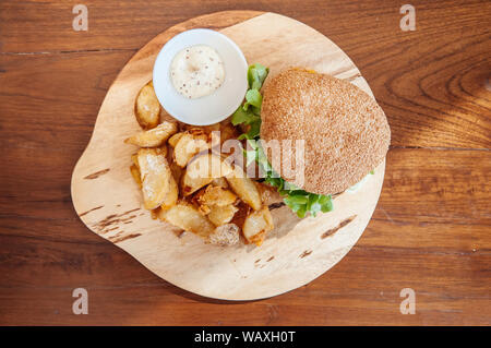 Cheeseburger bœuf, morceaux de pommes de terre frites avec sauce trempette ranch sur plaque en bois tourné Vue de dessus Banque D'Images