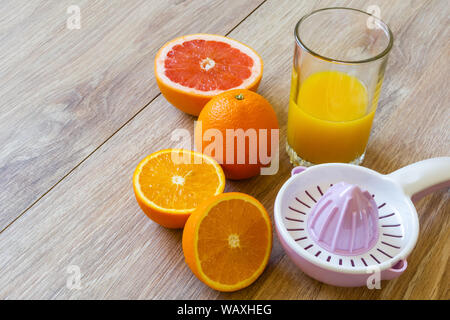 Still Life - ensemble et couper les oranges, l'aléseur manuel et verre de jus d'orange sur une table en bois Banque D'Images