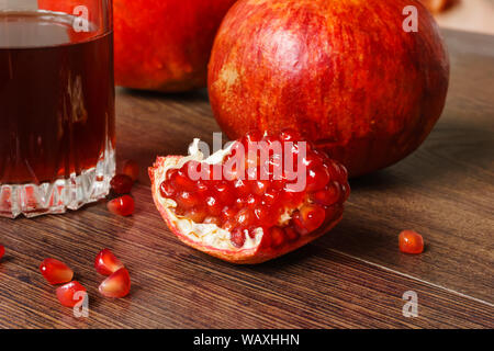 Stil life - toute rouge et fruits de grenade coupée et le verre de jus sur une table en bois foncé Banque D'Images