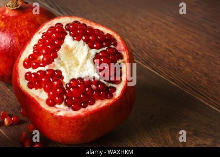 Stil life - toute rouge et coupé les fruits et graines de grenade éparpillés sur une table en bois foncé Banque D'Images