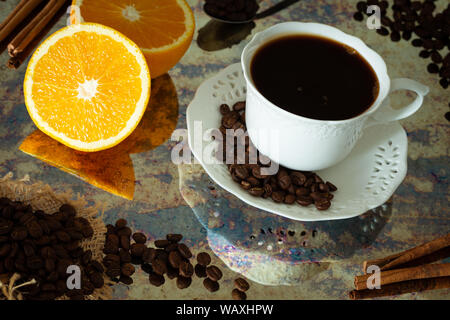Tasse de café noir avec des grains, l'orange et des bâtons de cannelle, Vintage style hygge Banque D'Images