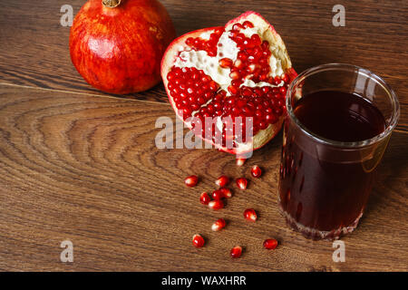 Stil life - toute rouge et coupé les fruits et graines de grenade éparpillés sur une table en bois foncé Banque D'Images