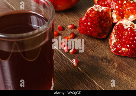 Stil life - ensemble rouge grenade coupée et fruits sur une table en bois foncé Banque D'Images