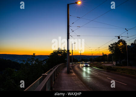 L'Allemagne, les voitures roulant sur une route à travers city Stuttgart dans le crépuscule aube magique après le coucher du soleil près de eugensplatz à côté des rails de tram en été Banque D'Images