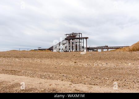 Paysage industriel désert avec rusty stationnaire séparateur gravitationnelle de sable et de gravier à l'horizon Banque D'Images