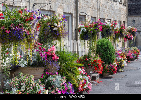 Paniers suspendus floral fleurs et des jardinières à l'extérieur de la tontine édifices le long de la colline, Cecily Cirencester, Cotswolds, Gloucestershire, Angleterre Banque D'Images