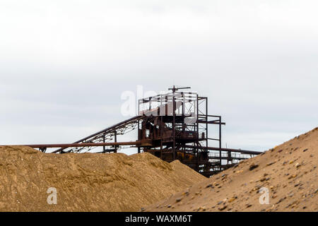 Paysage industriel désert avec rusty stationnaire séparateur gravitationnelle de sable et de gravier à l'horizon Banque D'Images