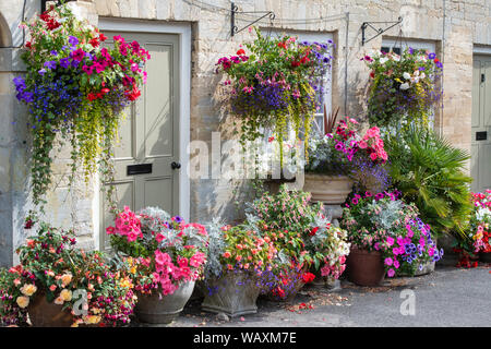 Paniers suspendus floral fleurs et des jardinières à l'extérieur de la tontine édifices le long de la colline, Cecily Cirencester, Cotswolds, Gloucestershire, Angleterre Banque D'Images