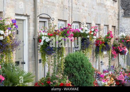 Paniers suspendus floral fleurs et des jardinières à l'extérieur de la tontine édifices le long de la colline, Cecily Cirencester, Cotswolds, Gloucestershire, Angleterre Banque D'Images