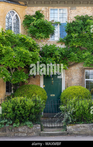 Le feuillage de glycines couvrant une maison le long de Cecily hill, Cirencester, Cotswolds, Gloucestershire, Angleterre Banque D'Images