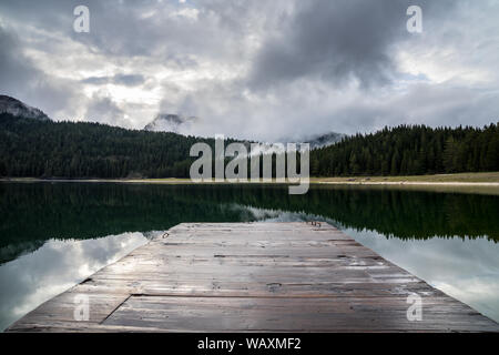 Le Monténégro, beau plan d'eau miroitant calme derrière de black lake landing stage en bois entouré par une forêt de conifères vert foncé nature paysage dans le brouillard Banque D'Images