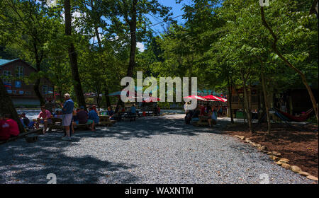 Durham, Caroline du Nord, USA - 3 août 2019 : au centre de plein air de Nantahala, les gens s'asseoir sous les parasols fournis sur tables picknic le long du Nant Banque D'Images