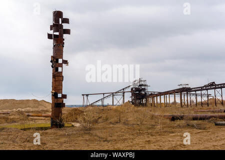 Paysage industriel désert avec rusty stationnaire séparateur gravitationnelle de sable et gravier, étrange tuyau rouillé qui ressemble à un totem sur le foregr Banque D'Images