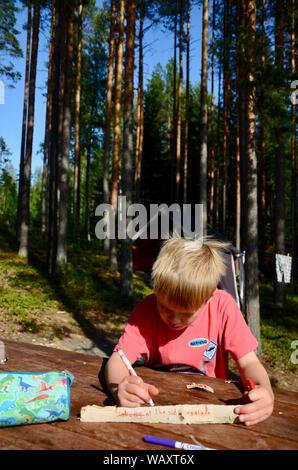 Jeune garçon peinture sur bois à table en bois finlandais à Lakeland, en Finlande. Banque D'Images