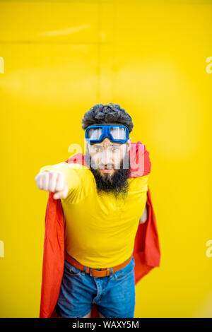 Portrait d'un homme comme un super héros dans des vêtements colorés et les lunettes pilote sur le fond jaune Banque D'Images