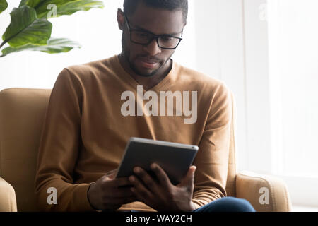 L'accent African American man in glasses using tablet computer Banque D'Images