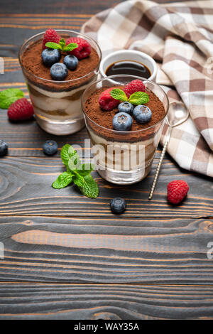 Dessert tiramisu classique avec les bleuets et les fraises dans une coupe en verre sur fond de bois Banque D'Images