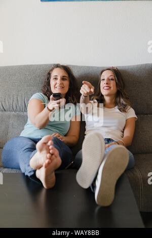 Les filles dans une table avec pieds d'une table devant la télévision Banque D'Images