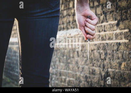Vol qualifié crime concept. Un voleur ou un tueur personne avec un couteau pointu sur le point de commettre un homicide, le meurtre des paysages. Banque D'Images