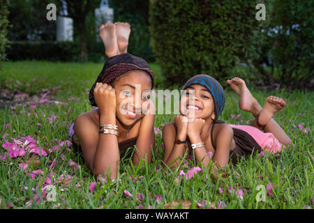 Portrait de deux sœurs course mixte reposant sur l'herbe et smiling at the camera Banque D'Images