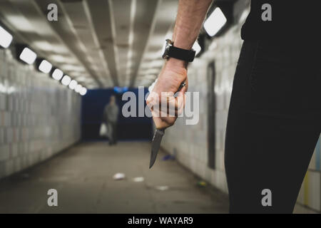 Vol qualifié crime concept. Un voleur ou un tueur personne avec un couteau pointu sur le point de commettre un homicide dans un tunnel. Banque D'Images