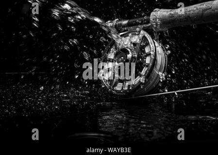 Canne et moulinet de pêche à la mouche avec de l'eau pulvérisée sur le noir dans le noir et blanc Banque D'Images