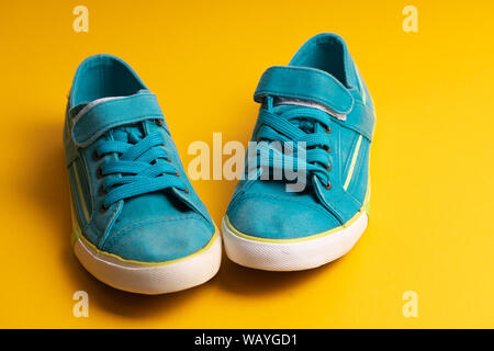 L'enfant bleu chaussures de sport avec un seul blanc d'un tue-mouches sur un fond jaune Banque D'Images