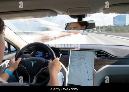 Homme conduisant Tesla Model S en voyageant sur une route très fréquentée. (Longue exposition) Banque D'Images