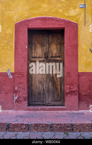 Vieille porte en bois et mur sur une maison jaune et rouge au Mexique village vieille ville Banque D'Images