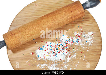 Un rouleau à pâtisserie en bois sur une planche à découper en bambou avec de la farine blanche et multicolore arrose au conseil isolated on white Banque D'Images